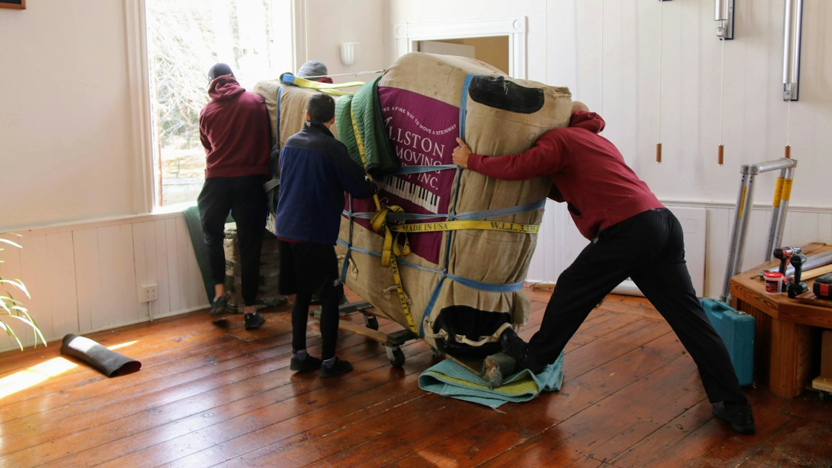 Movers moving wrapped furniture on a dolly